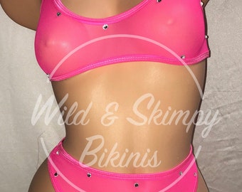 Könnte beinhalten: Ein rosafarbener Mesh-Bikini mit silbernen Strasssteinen. Das Oberteil hat einen runden Ausschnitt und dünne Träger. Das Unterteil ist hochgeschnitten.