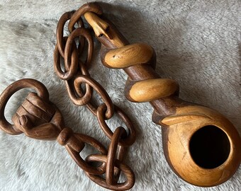 Carved wood chain with fist, gourd/egg, spiral serpent.