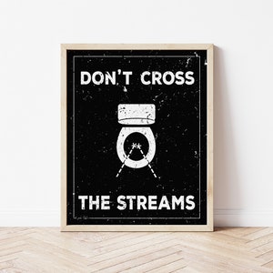 May include: A black and white poster with a distressed, vintage look. It features a toilet with a toilet brush and the text "DON'T CROSS THE STREAMS".