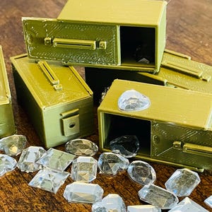 May include: Five small, green, rectangular boxes with lids. Each box has a slot on the front and a latch on the side. The boxes are open and contain clear, faceted gems.