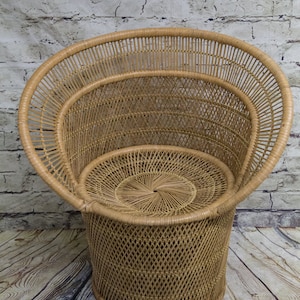 May include: A woven wicker chair with a round, open back and a circular seat. The chair is made of natural brown wicker and has a unique, modern design.