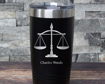 May include: Black stainless steel tumbler with a silver lid and a laser engraved image of a scale of justice and the text "Charles Woods".