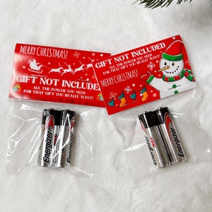 May include: Two clear plastic bags with red and white Christmas gift tags that say "Gift Not Included" and "Merry Christmas!"  The bags contain three AA batteries each, labeled "Energizer Max".