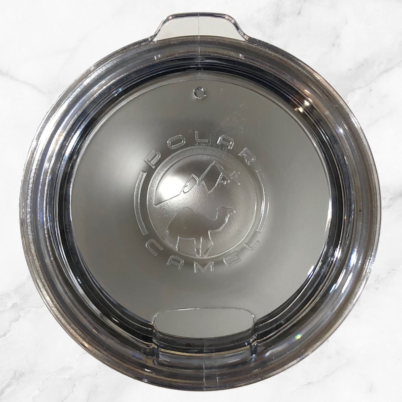 May include: A clear plastic lid with a silver rim and a black and white logo that says "Polar Camel" with a camel silhouette inside the logo.