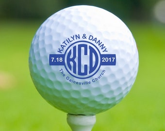 May include: A white golf ball with a blue circle design that says "Katelyn & Danny 7.18 The Gainesville Church 2017" and the initials "KCD" in the center.