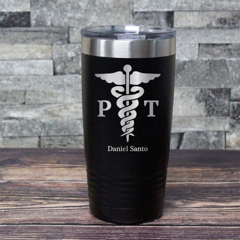 May include: Black stainless steel tumbler with a silver lid. The tumbler has a white caduceus symbol with the letters "PT" on either side of the symbol. The text "Daniel Santo" is engraved below the symbol.