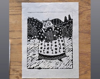 May include: Black and white linocut print of a cat wearing a hooded dress and playing an accordion in a forest setting.