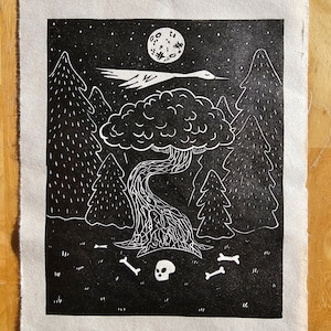 Peut inclure: Gravure sur linoléum en noir et blanc représentant une scène de forêt effrayante avec un crâne, des os, un arbre, un oiseau en vol et une pleine lune.