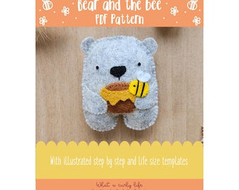May include: A felt bear holding a honey pot and a bee. The bear is gray with a black nose and eyes. The honey pot is brown and yellow, and the bee is yellow and black. Text on the image reads "Bear and the bee PDF Pattern".