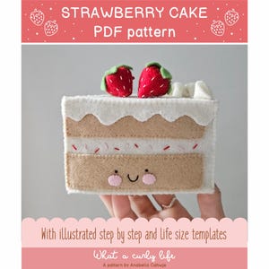 May include: A felt strawberry cake slice with a smiling face, topped with two red strawberries and white frosting. The text "STRAWBERRY CAKE PDF pattern" is at the top. The bottom text reads "With illustrated step by step and life size templates".