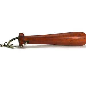 May include: A small, reddish-brown wooden baseball bat keychain. It features a metal ring and chain for attaching to keys or a bag. The bat is a miniature replica of a full-sized baseball bat.