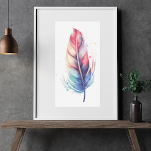 Può includere: Una stampa incorniciata ad acquerello di una piuma colorata. La piuma presenta sfumature di rosa, giallo, blu e verde, con schizzi di vernice sui bordi. L'opera d'arte è esposta in una cornice bianca.