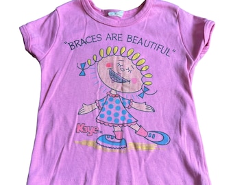 vintage girls tshirt Braces are Beautiful Kaye Pink 70s 80s. Condition: some wash wear fading but good overall See photos for details please