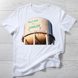 May include: White t-shirt with a graphic of a water tower. The water tower has the text "BILLY BOB ♥ CHARLENE" written on it.