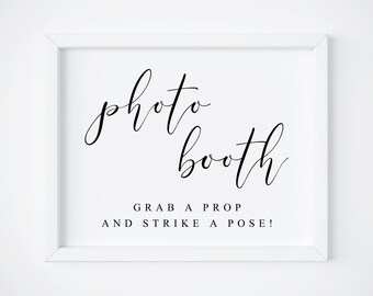 May include: White framed sign with black calligraphy that reads "photo booth" and the text "Grab a prop and strike a pose!"