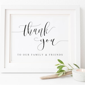 May include: A white framed print with black calligraphy that reads "thank you" and "to our family & friends".