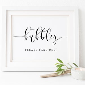 May include: White framed sign with black calligraphy that reads "bubbles" and "please take one".