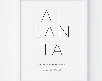 May include: A black and white print with the word "ATLANTA" in large, bold letters. The text "33.7490° N, 84.3880° W" and "United States" are printed below the city name.