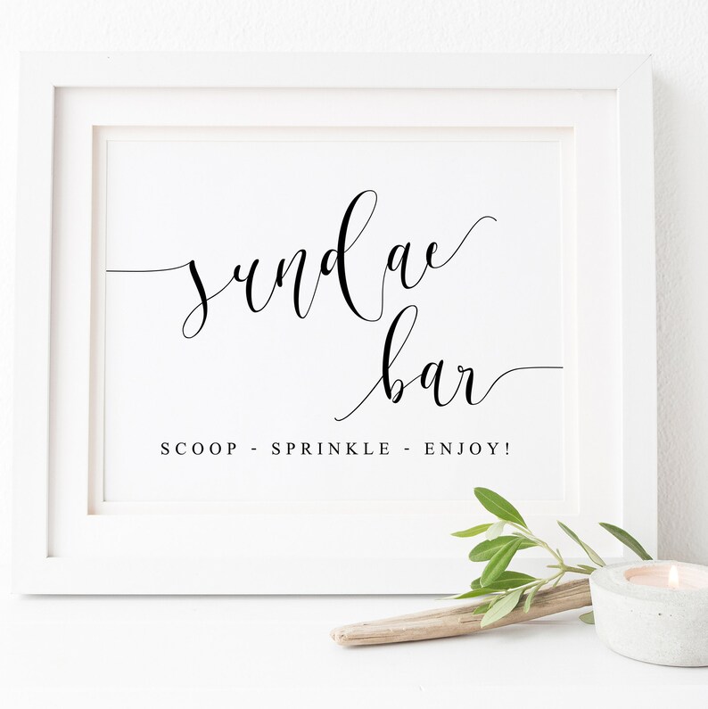 May include: White framed sign with black calligraphy that reads "sundae bar" and the text "SCOOP - SPRINKLE - ENJOY!"