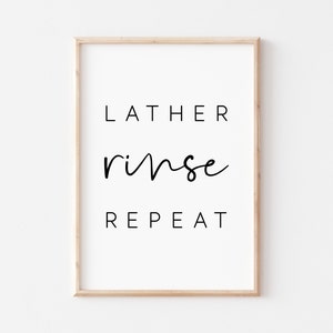 Puede incluir: Una impresión enmarcada con el texto "LATHER rinse REPEAT" en letras negras sobre un fondo blanco.