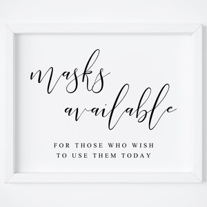 May include: White framed sign with black calligraphy text that reads "masks available" and "for those who wish to use them today".