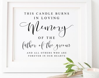 May include: White framed sign with black text that reads "This candle burns in loving memory of the father of the groom and all others who are forever in our hearts."