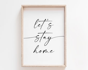 May include: A framed print with the text "let's stay home" in black cursive script on a white background.