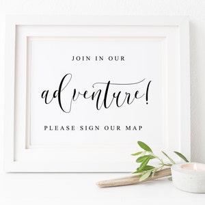 May include: White framed sign with black text that reads "Join in our adventure! Please sign our map".