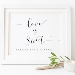 May include: White framed sign with black calligraphy that reads "love is sweet" and the text "Please take a treat".