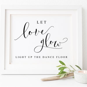May include: White framed sign with black calligraphy that reads "Let love glow" and "Light up the dance floor".