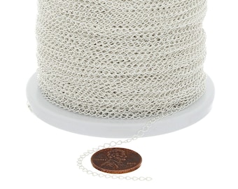 May include: A spool of silver-colored chain with a delicate, open weave pattern. A small length of the chain is unraveled, next to a penny for size comparison. The chain is likely used for jewelry making or other craft projects.