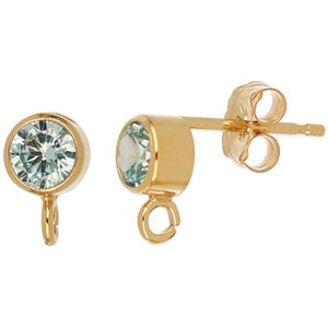 May include: A pair of gold-tone earrings with a small, round, light blue gemstone and a dangling loop. The earrings have a post back.