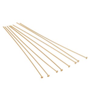 May include: Ten gold-colored headpins are neatly arranged in a fanned-out pattern against a white background. These straight pins are slender and feature small, round heads.  The pins are uniform in length and color, suggesting they are a set of jewelry-making supplies. The image showcases the fine details of the headpins, highlighting their smooth texture and consistent shape. These headpins are ideal for crafting earrings, necklaces, and other jewelry projects.