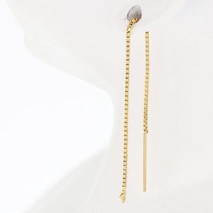 Może przedstawiać: Para długich złotych kolczyków z łańcuszka z prostym złotym prętem zwisającym z dołu każdego łańcuszka.