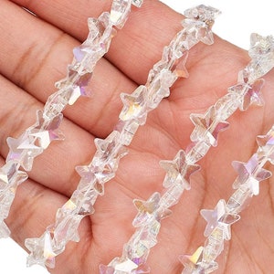 May include: A strand of iridescent clear star-shaped beads. The beads are strung on a clear thread and are arranged in a repeating pattern.