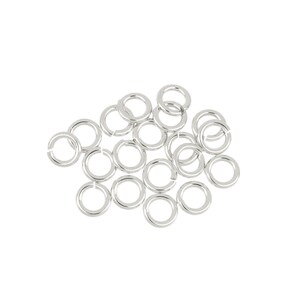 May include: A pile of silver jump rings, a type of jewelry finding used for connecting chains, cords, and other jewelry components.