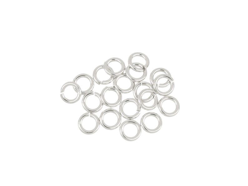 May include: A pile of silver jump rings, a type of jewelry finding used for connecting chains, cords, and other jewelry components.
