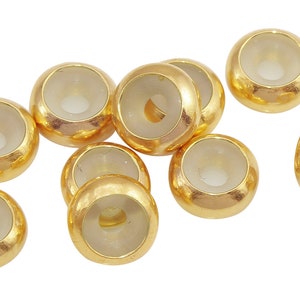 May include: Ten gold-colored beads with clear glass centers. The beads are round and have a hole in the center.