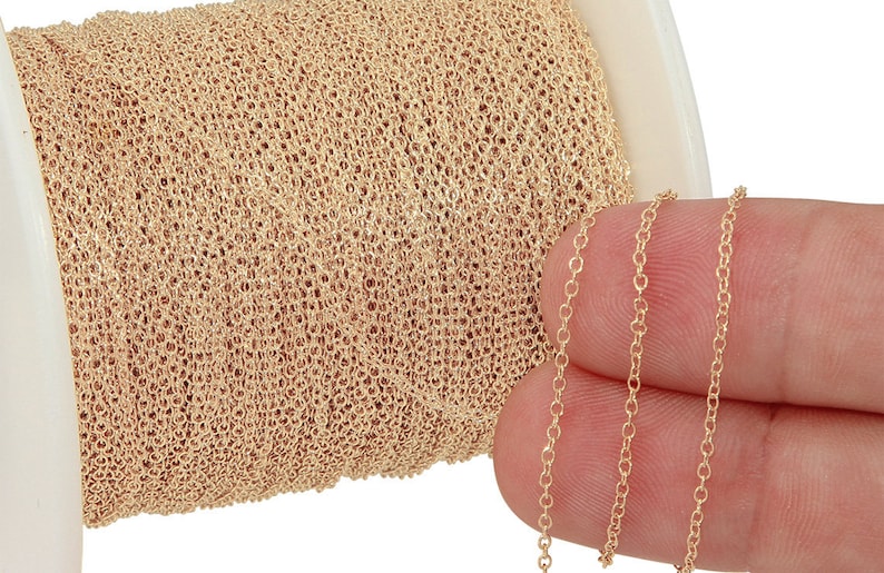 Puede incluir: Un carrete de cadena de color dorado, con una longitud de la cadena mostrada en un dedo.