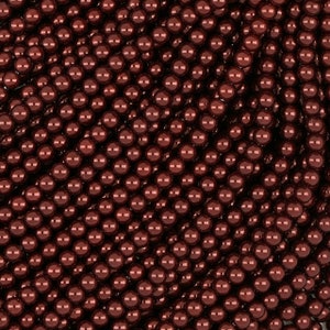 Op de afbeelding: Een close-up van een grote hoeveelheid kleine, ronde, donkerbruine kralen. De kralen zijn in een willekeurig patroon gerangschikt, waardoor een textuur ontstaat.