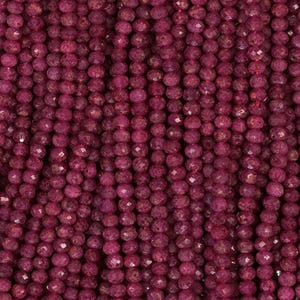 May include: Close-up of a collection of faceted, round, deep red beads. The beads are strung together, creating a textured, vertical pattern. The beads have a slightly irregular shape and a polished, reflective surface.