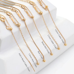 Peut inclure: Gros plan sur huit chaînes en or de styles et de tailles différents. Les chaînes sont étiquetées avec leurs noms et leurs dimensions, notamment Chaîne câble 1,2 mm, Chaîne câble 1,7 mm, Chaîne boule à billes, Chaîne boîte, Chaîne rolo 1,3 mm et Chaîne câble à ajouter une perle.
