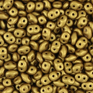 以下が含まれることがあります： 金色の小さなガラスビーズが大量に写っているクローズアップ。ビーズは不規則な形をしていて、マットな仕上がりです。