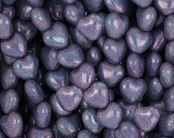 May include: A close-up of a pile of iridescent purple heart-shaped beads. The beads have a slightly textured surface and a subtle shimmer.