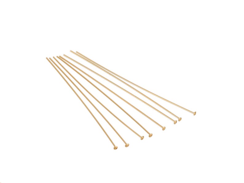 May include: Ten gold-colored headpins are neatly arranged in a fanned-out pattern against a white background. These straight pins are slender and feature small, round heads.  The pins are uniform in length and color, suggesting they are a set of jewelry-making supplies. The image showcases the fine details of the headpins, highlighting their smooth texture and consistent shape. These headpins are ideal for crafting earrings, necklaces, and other jewelry projects.