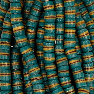 Puede incluir: Primer plano de cuentas de vidrio azul turquesa con finas rayas doradas y marrones. Las cuentas están dispuestas en un patrón aleatorio, mostrando los intrincados detalles de las rayas.