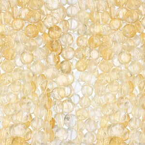 May include: Close-up of a collection of faceted, translucent beads in shades of yellow and clear. The beads are strung together, creating a textured, layered effect. Ideal for jewelry making or craft projects.