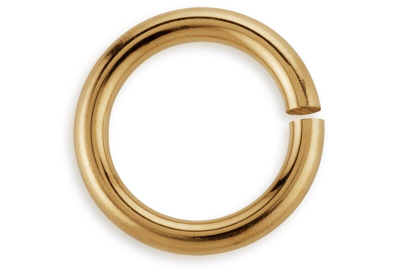 May include: Gold jump ring, a circular metal ring with a gap, used for jewelry making and crafting.