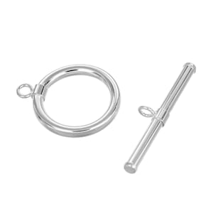 May include: A silver-colored toggle clasp, consisting of a circular ring and a straight bar with a small loop. The clasp is designed for jewelry making and is shown against a white background. The ring is approximately 1 inch in diameter.