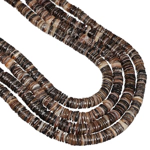 May include: A multi-strand necklace composed of numerous small, flat, circular beads in varying shades of brown, black, and cream. The beads are arranged in several parallel rows, creating a layered effect with a smooth, polished texture.